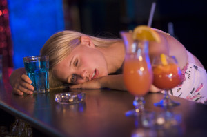 Drunk young woman resting head on bar counter